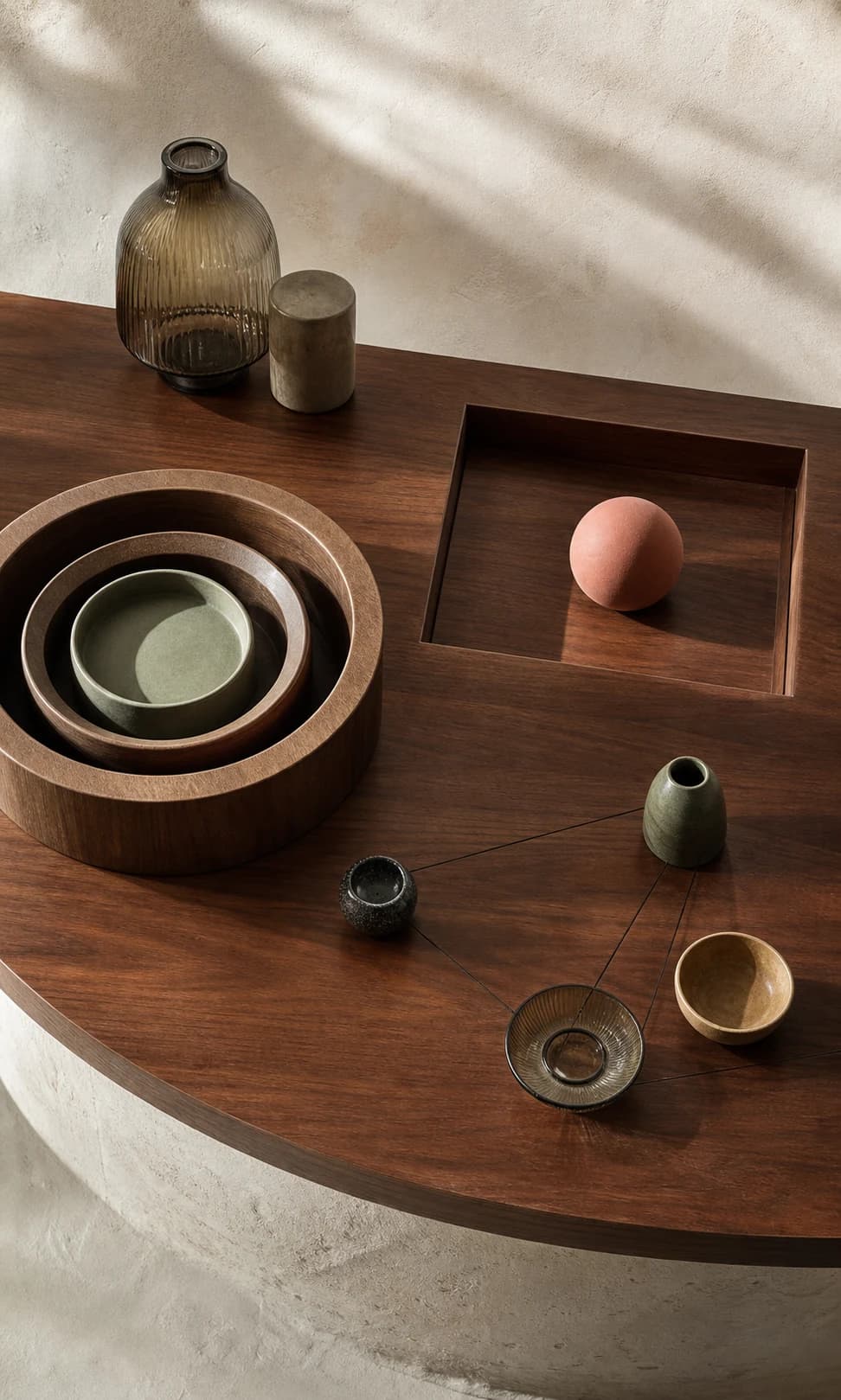 An editorial still life of nested wooden rings, a focused peach sphere, and connected ceramic vessels.